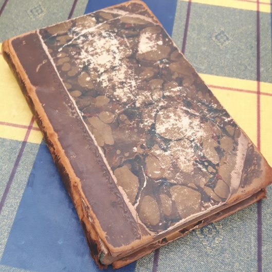 The binding is battered and the hinges tired - it has clearly been well read since it was last bound.